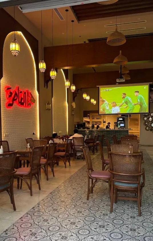 Café dining room with arched walls, brass lanterns, rattan chairs and patterned floor tiles