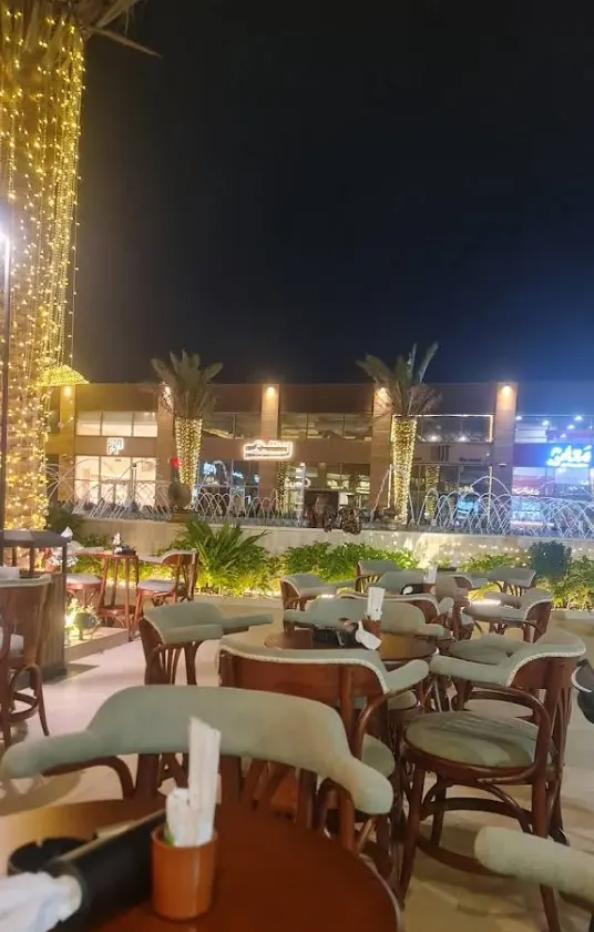 Terrace seating beside the plaza fountains and illuminated palm trees
