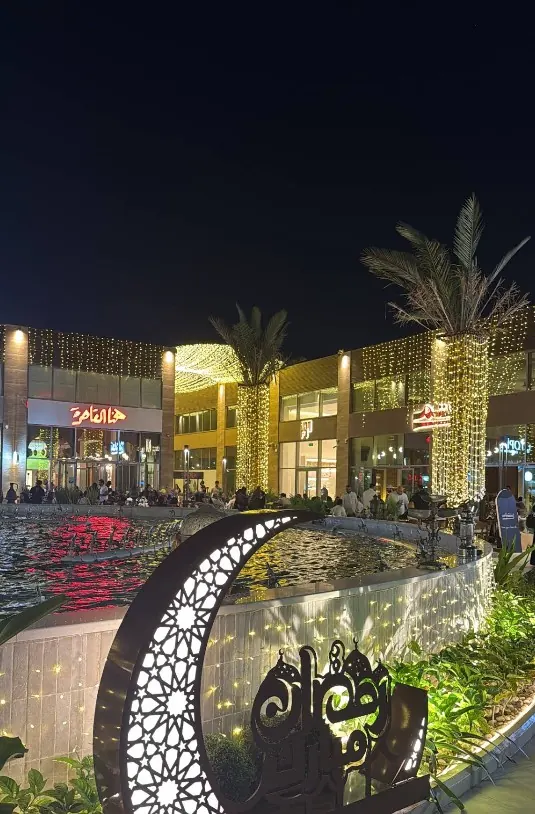 The fountain plaza at night with an illuminated crescent and lit palm trees
